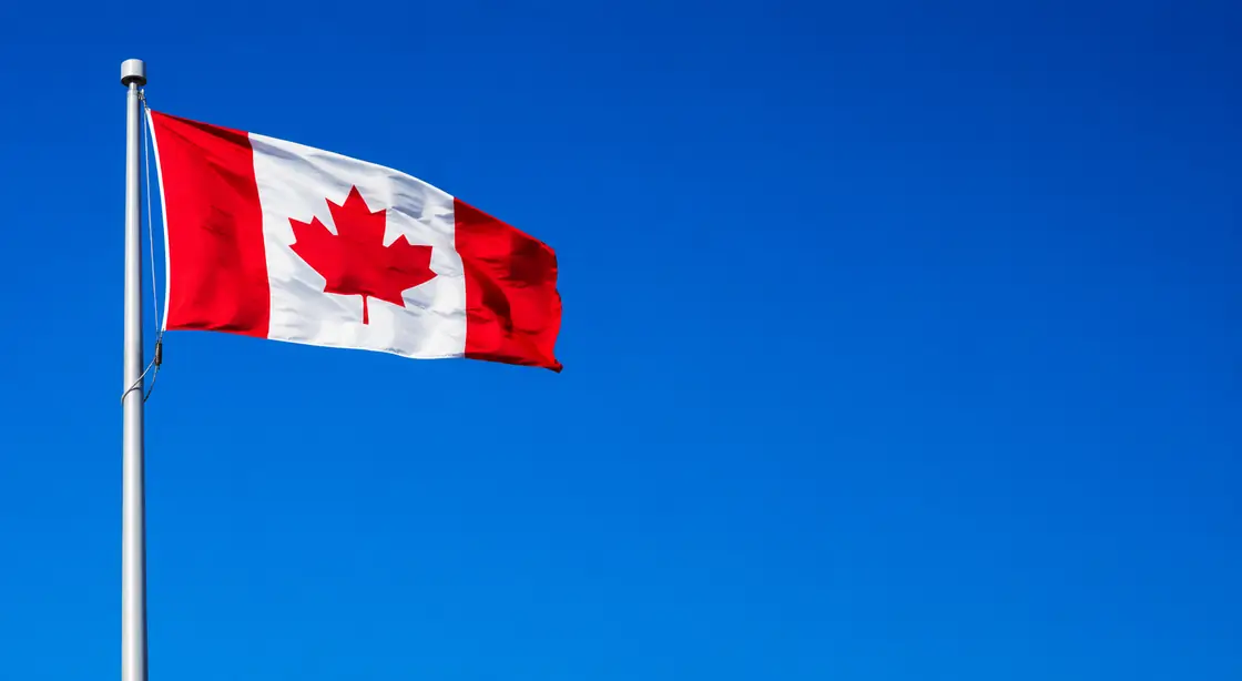 Canadian flag flying against a clear blue sky, for importers comparing customs brokers across Canada