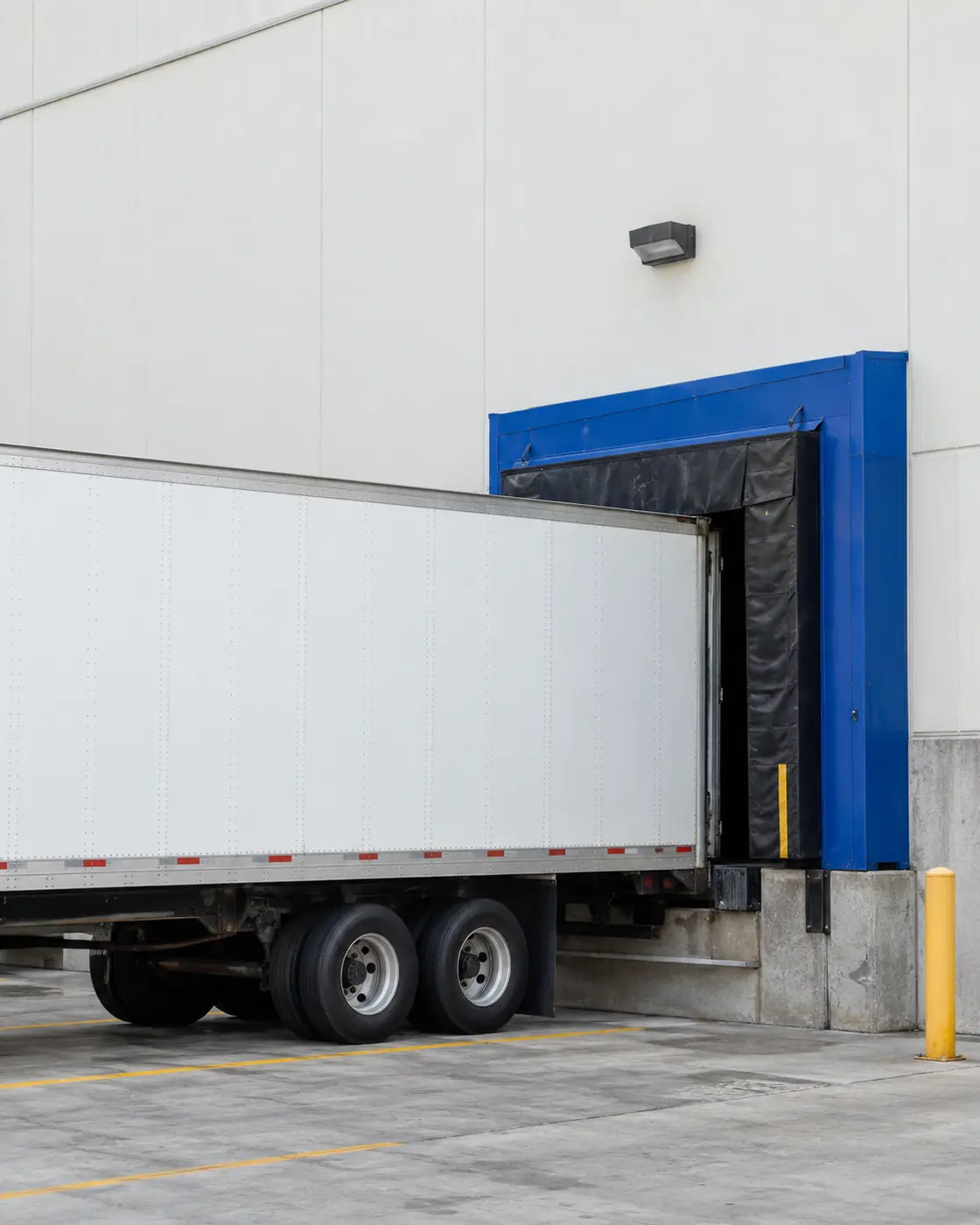Trailer backed into a blue loading dock door at a commercial warehouse